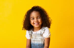 little girl smiling with yellow background