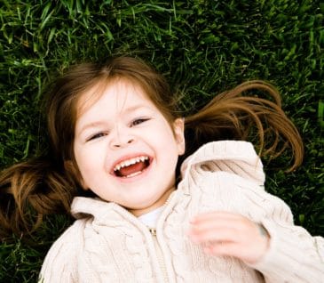 little girl smiling laying in grass