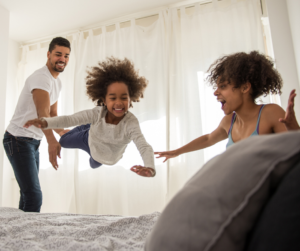 little girl jumping on bed with parents